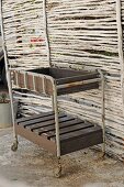 Old trolley with home-made wooden inserts against screen in garden