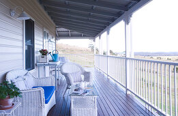 White wicker patio furniture on the veranda of a wooden country home