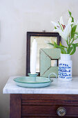 Vintage candlestick holder next to a vase with white lilies on a chest of drawers