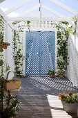 Garden shed made from white lattice panels and plant pots on the wooden floor