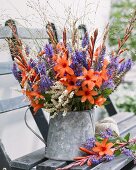 Sommerlicher Blumenstrauss im Zinkkrug auf Gartenbank