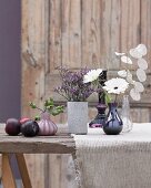 Flower vases and plums on a wooden table