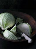 White cabbage, partially sliced, in a wooden bowl