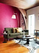 Modern living room in former church with antique ceiling beams, purple wall and large animal-skin rug