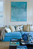 Turquoise couch below watercolour in the same shade; bouquet of blue hydrangeas on coffee table in foreground