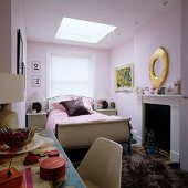 Partially visible dressing table in front of sleigh bed and open fireplace in traditional bedroom painted pastel lilac