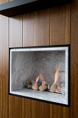 Gas fire with marble cladding and pebbles integrated into wooden wardrobe doors