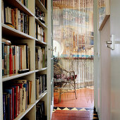 Narrow hallway with built-in bookcase and view through strip curtain hanging in open doorway