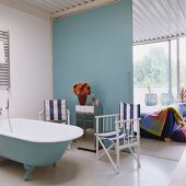 Maritime ensuite bathroom with director's chairs next to retro bathtub and view into loft apartment bedroom