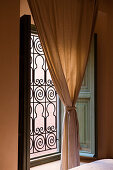 Gathered curtain in front of window with Moroccan-style grille