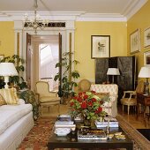 Herrschaftliches Wohnzimmer in Gelb mit Sofa und antiken Sesseln um Couchtisch