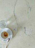 An empty coffee cup and a water glass on a marble table