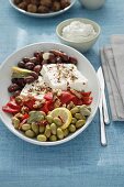 A Greek appetizer platter with olives, pepper and feta cheese