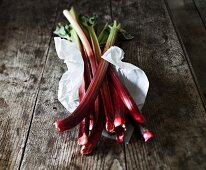 Fresh rhubarb in paper on a wooden surface