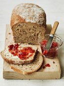 Organic country bread on a chopping board with strawberry jam