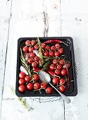 Cherry tomatoes with herbs and chilli pepper on a baking tray
