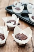 Chocolate muffins in parchment paper, some in a muffin tray