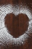 Icing sugar on a wooden surface creating a heart shape