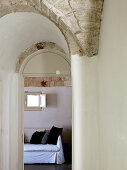 Vaulted anteroom and view through arched doorway of sofa with white loose cover and black cushions