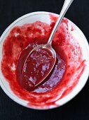 Raspberry sauce in a bowl with a spoon (close-up)