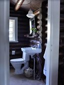View of modern bathroom in log cabin through open door