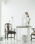 Fur cushion on antique armchair and modern table in white room