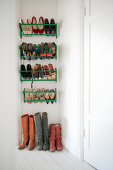 Ladies' shoes in green metal shoe racks on wall and boots on hall floor