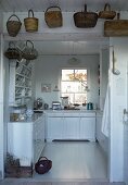 Baskets hanging above open doorway leading to country house kitchen