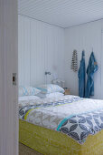 Blick durch offene Tür auf Doppelbett mit Bettwäschenbezug in schwedischem Look in weißem holzverkleideten Schlafzimmer