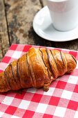 A chocolate croissant on a checked cloth
