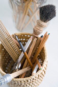 Basket holding paintbrushes, ink pens and coloured pencils