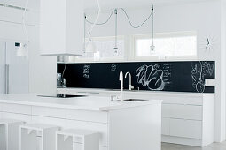 White designer kitchen with black splashback; simple, wood-frame bar stools at kitchen island