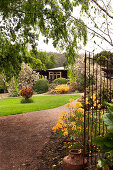 View of house in well-tended gardens through open garden gate