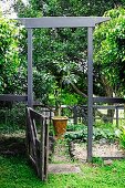 Summery garden - open garden gate with tall, wooden door-like frame and view of potted plant