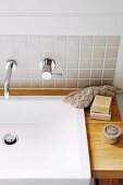 Modern vanity - sink with wooden counter and designer wall faucet on a tiled wall