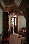 Corner of grand living room with display cabinet and armchair next to door with transom window