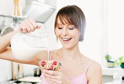 A woman pouring milk over muesli