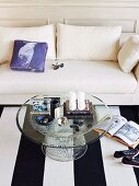 Sitting area in living room with white sofa, black and white striped carpet and round glass table