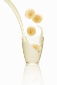 Banana slices falling into a glass of milk