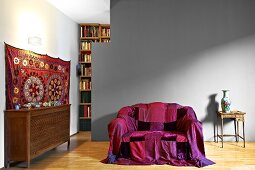 Brightly coloured throw on sofa in front of grey-painted partition in modern living room with traditional ambiance
