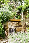 Birdbath on rough stone block in Mediterranean garden