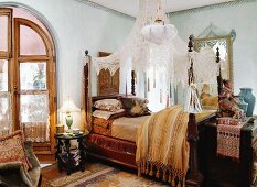 Style mix - antique canopy bed with transparent curtain in a bedroom with oriental influences