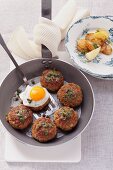 Meat balls with a fried egg, caper butter and sardines