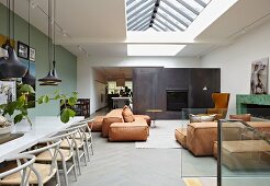 Moderner Wohnraum mit Klassikerstühlen am Essplatz und gemütliche Bodenpolster in Loungebereich unter Oberlicht