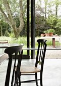 Dining table and Chiavari chairs in front of sliding glass doors leading to garden