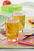 Two glasses of sparkling apple juice with school things