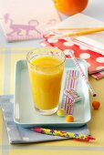A glass of orange juice and a small tray with school things