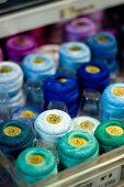 Spools of thread in various shades of blue in storage box