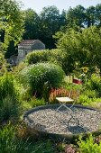 Folding chair on circular gravel area in Mediterranean garden