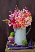 Late summer still-life with large bouquet of snapdragons in zinc jug and spiky sweet chestnuts on folded linen cloth